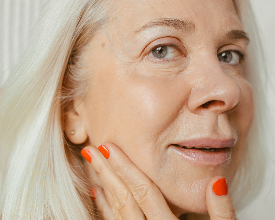 Middle-aged woman in her 50s gently touching her face, showcasing smooth skin after anti-ageing injectables.