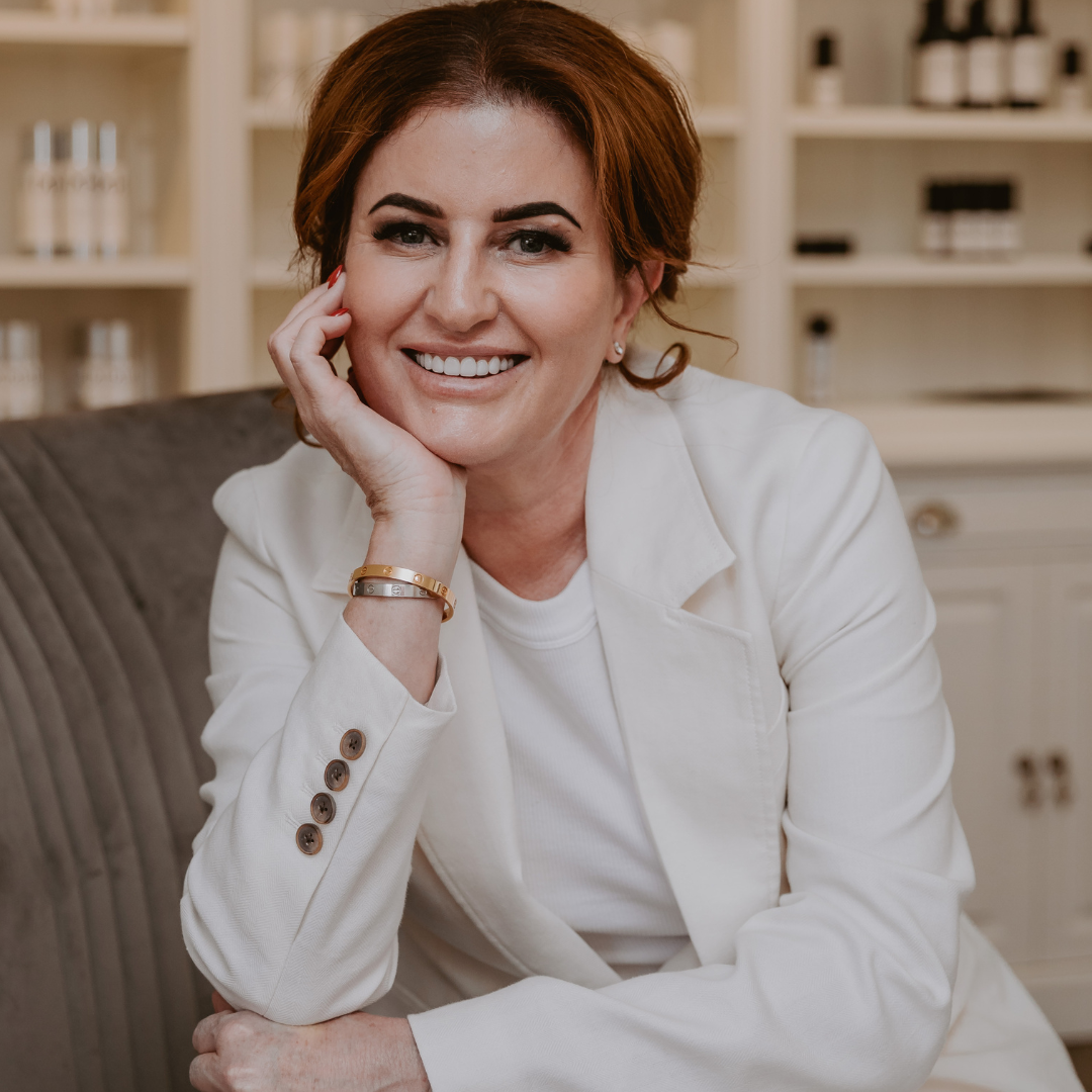 Mel Hornery, owner of Mel Hornery Cosmetics, sitting in front of her skin care range, showcasing her dedication to skincare and beauty.